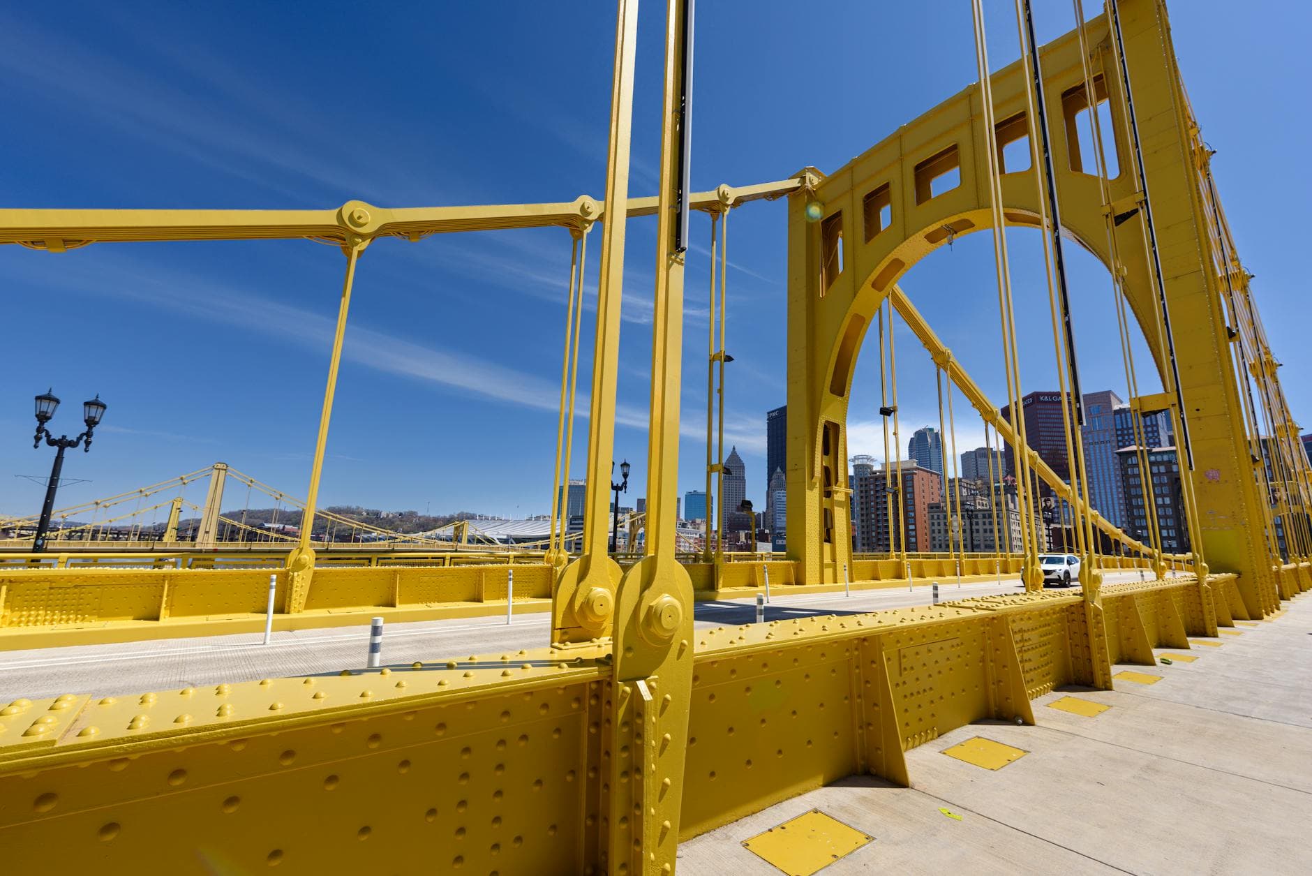 Pittsburgh cityscape with a vibrant yellow suspension bridge and downtown skyline on a bright sunny day